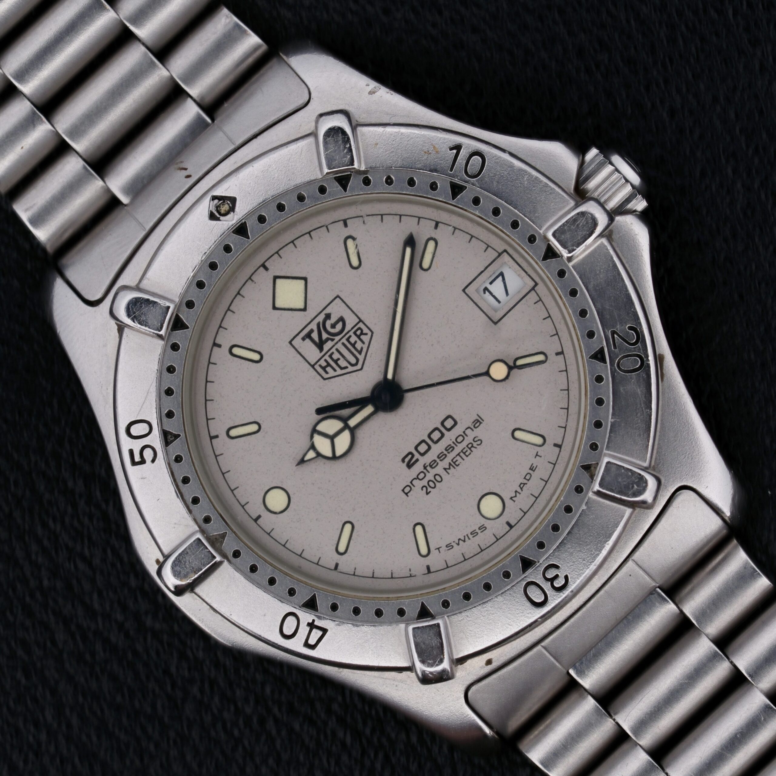 The Tag Heuer Professional 2000 Ref 962.206 is a Swiss-made quartz watch from the 1990s, featuring a 38mm stainless steel case and original stainless steel bracelet. Its gray dial with silver-toned hands and indices ensures readability, while the central seconds hand, hack second function, and rotating bezel add precision and functionality. With a 20mm lug width, it offers a comfortable fit and a minimalist, uncluttered design, making it a versatile and stylish choice for both daily wear and special occasions.